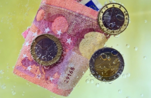 Bild: Euro-Münzen und Euro-Scheine in einer Flüssigkeit. EU-Geldwäscherichtlinien: Ursachen statt Symptome bekämpfen!